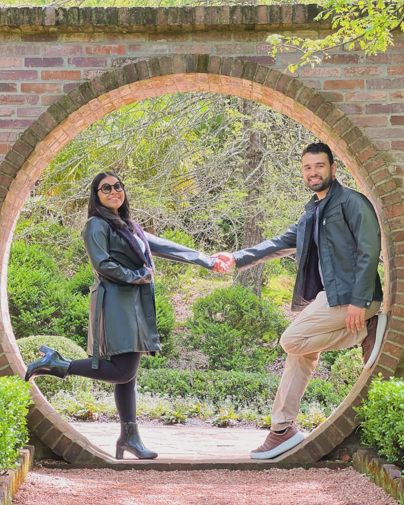 Casal de mãos dadas no arco circular de tijolos em meio ao jardim