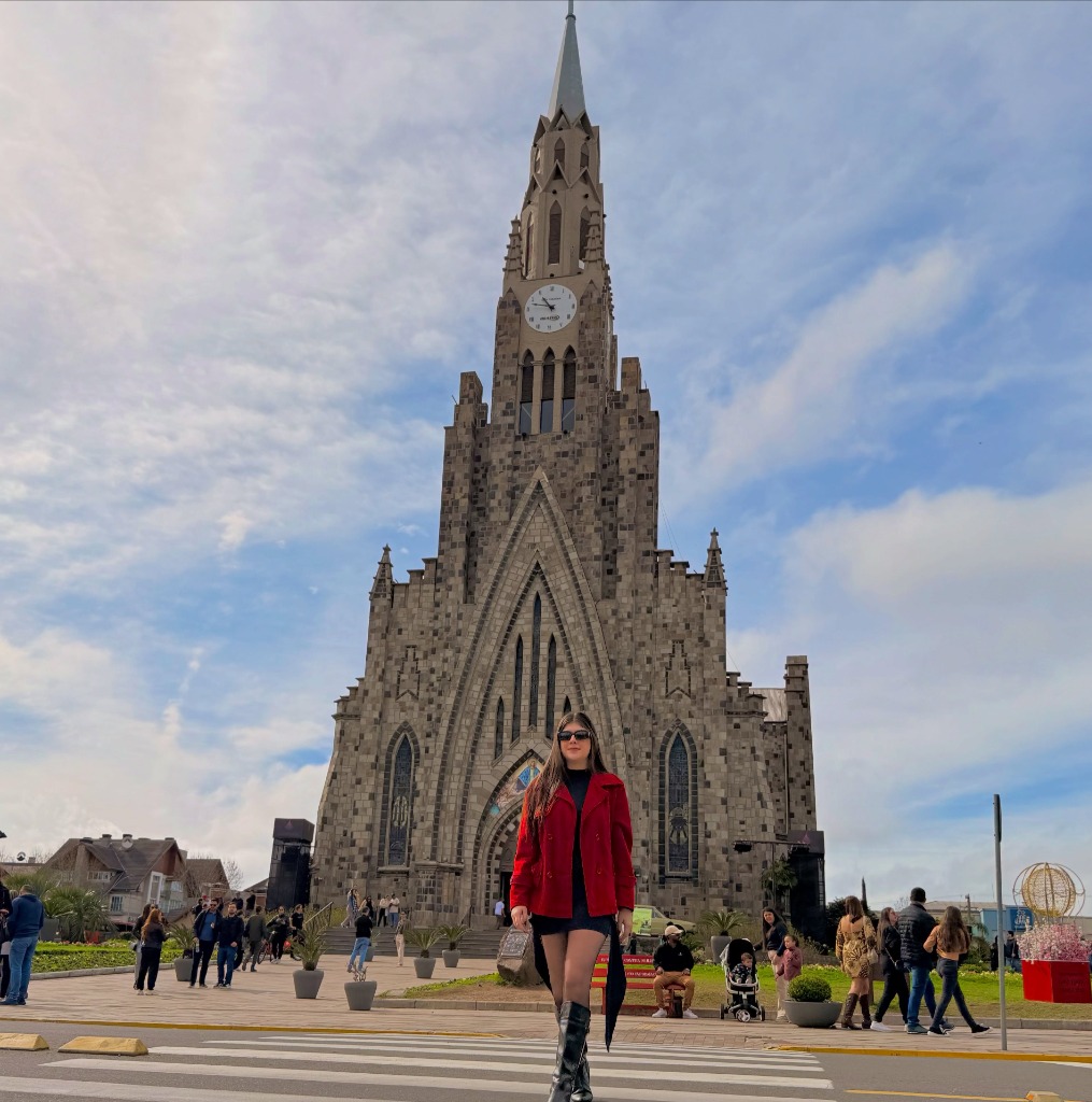 Mulher com casaco vermelho em frente à Catedral de Pedra de Canela